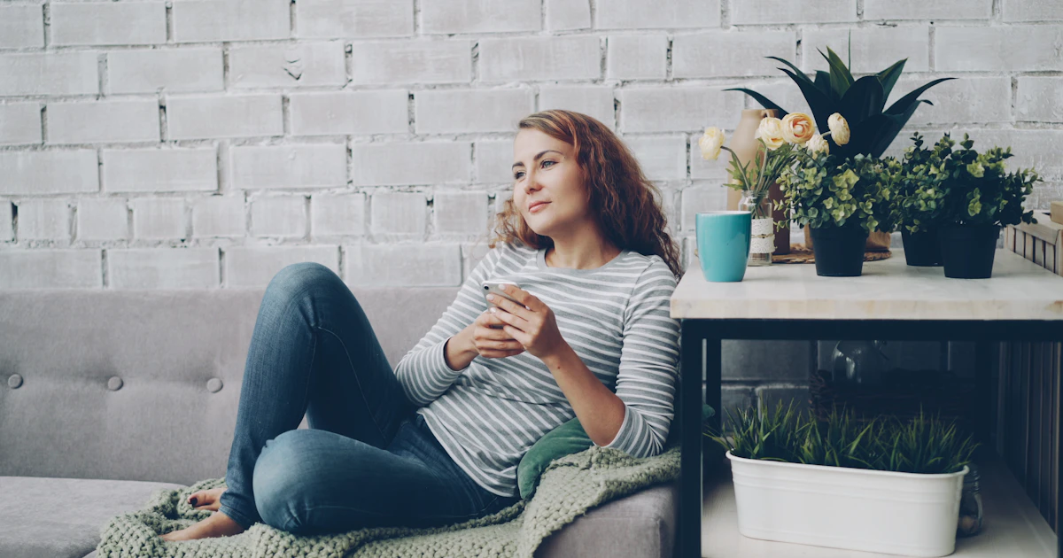 Voyageuse consultant le livret d'accueil numérique sur son smartphone dans le salon du logement