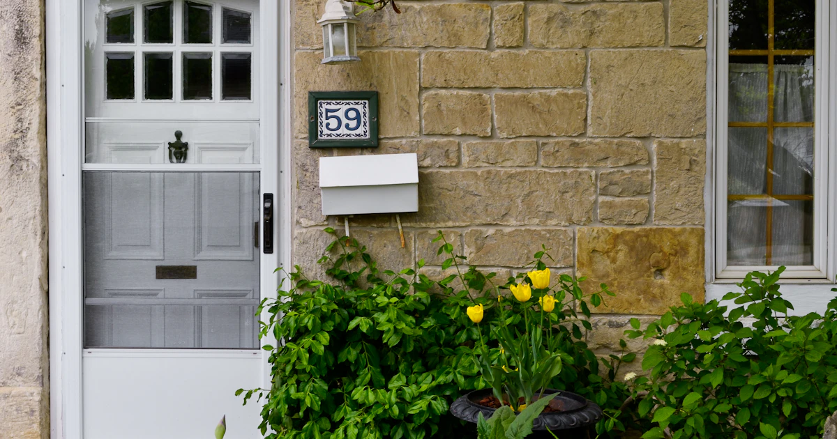 Entrée de maison en pierre avec boîte murale fixée à hauteur d'homme à côté de la porte, emplacement type pour une boîte à clés de location